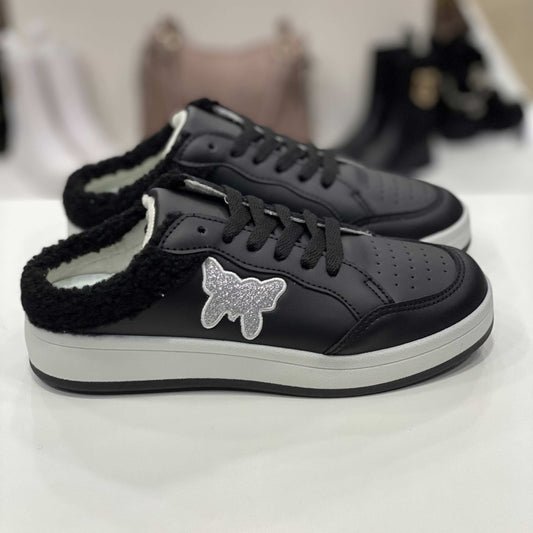 Sneakers a ciabatta nere con decorazione a forma di farfalla glitterata e interno in peluche nero, vista laterale su sfondo neutro