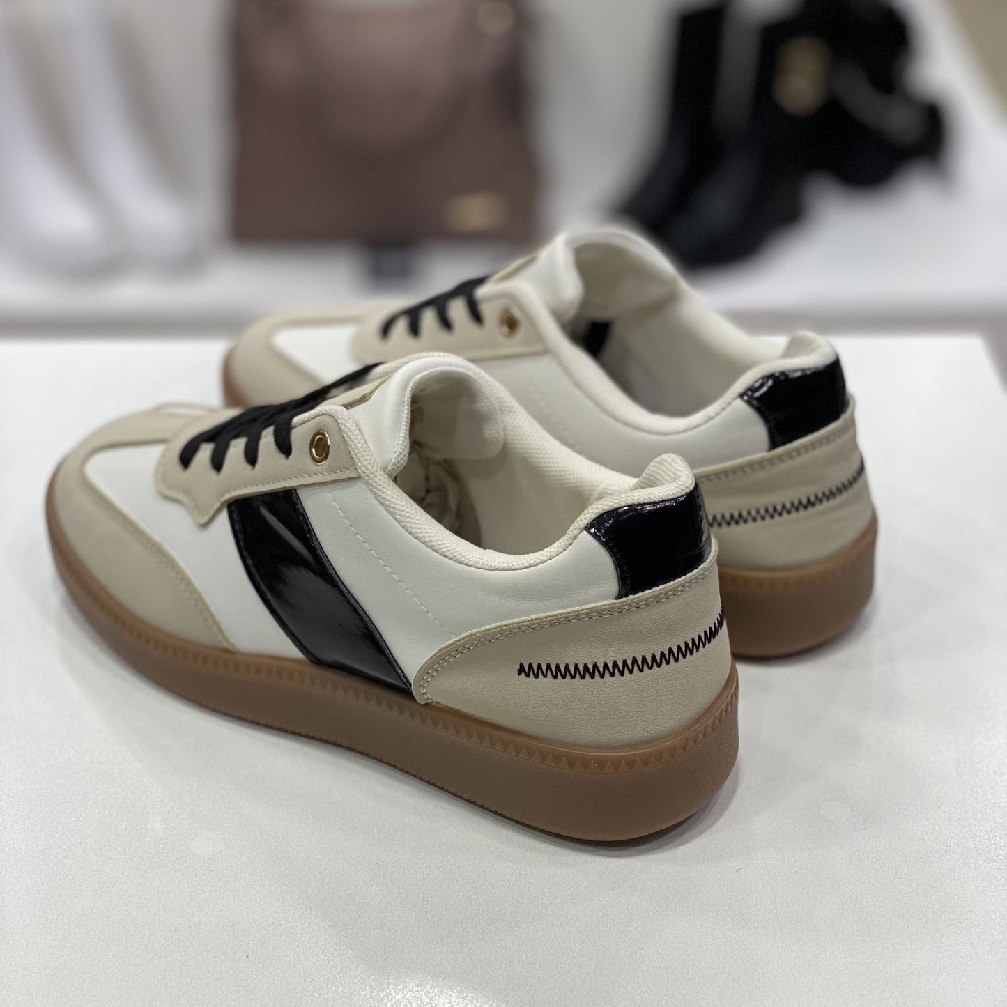 Parte posteriore di sneakers bianche e beige con suola in gomma, vista del tallone su sfondo neutro