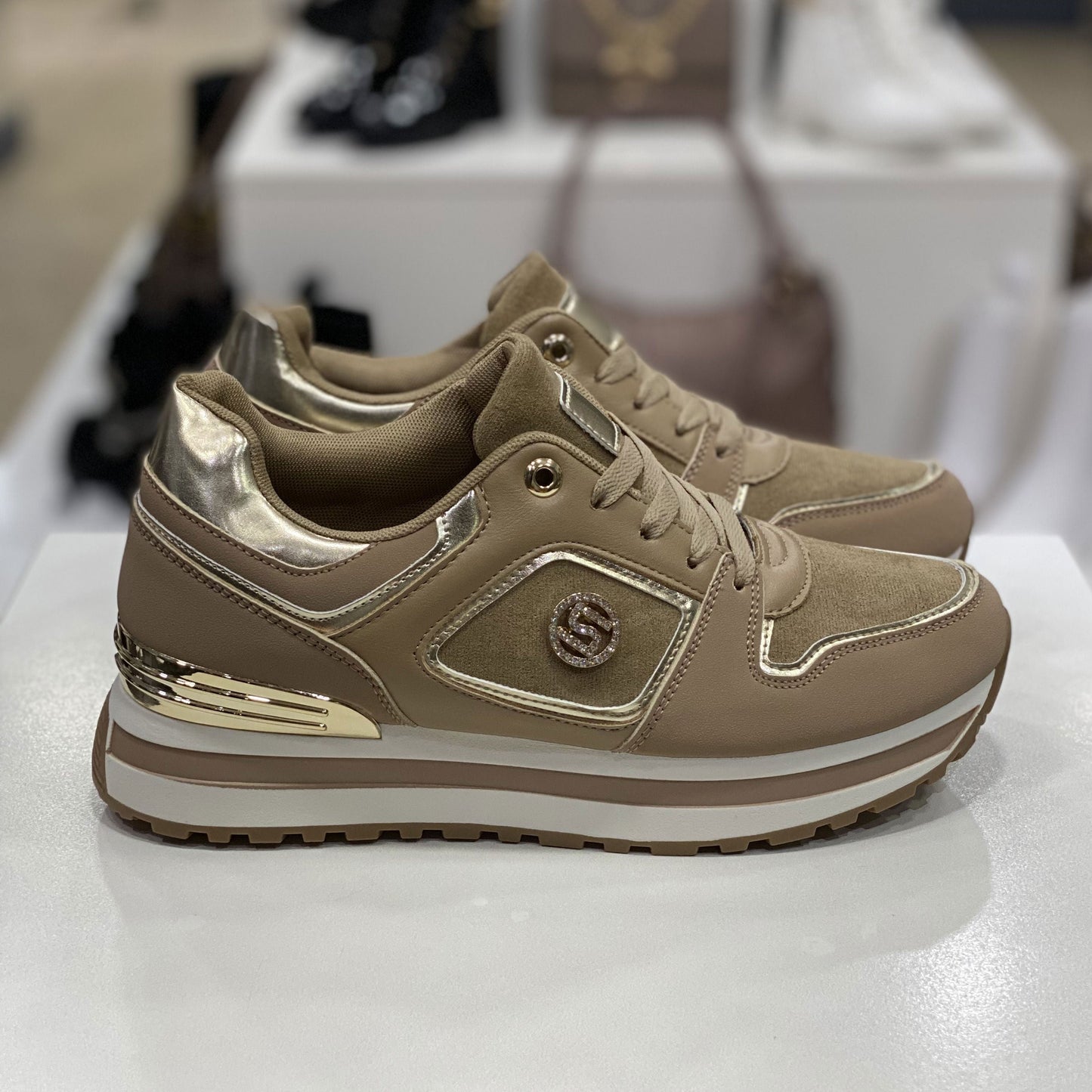 Sneakers beige con dettagli metallici dorati, vista laterale su sfondo neutro