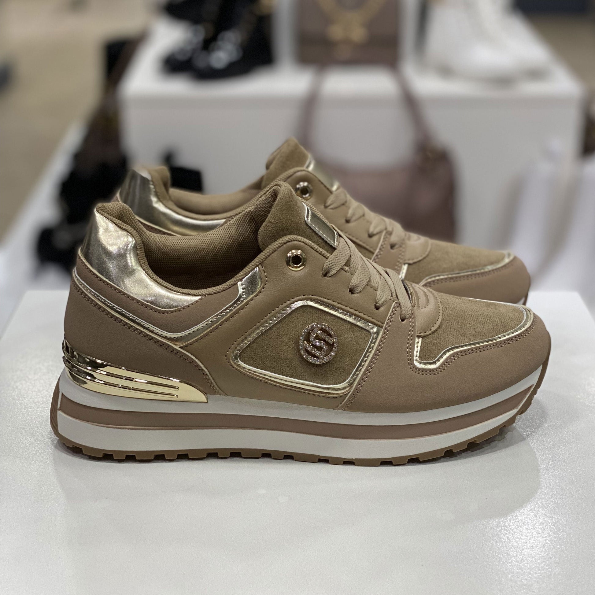 Sneakers beige con dettagli metallici dorati, vista laterale su sfondo neutro