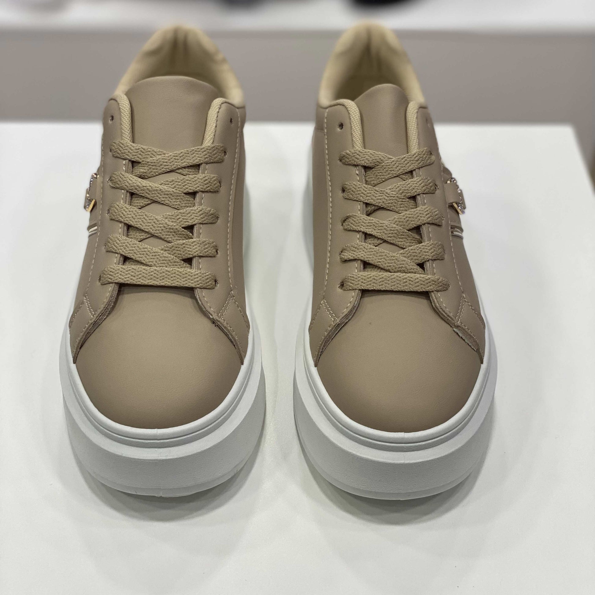 Sneakers beige con rifiniture dorate e suola alta, vista frontale su sfondo neutro