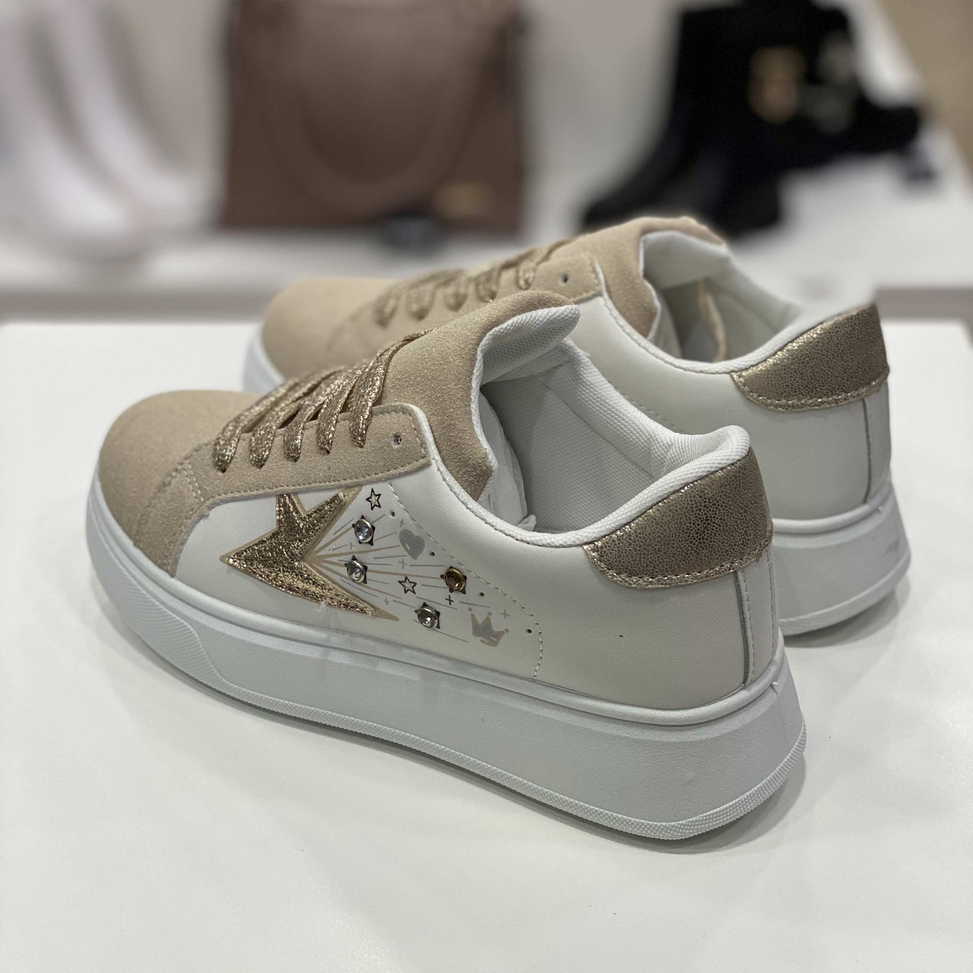 Parte posteriore di sneakers beige con tallone decorato a pois dorati e dettagli eleganti, vista del tallone su sfondo neutro