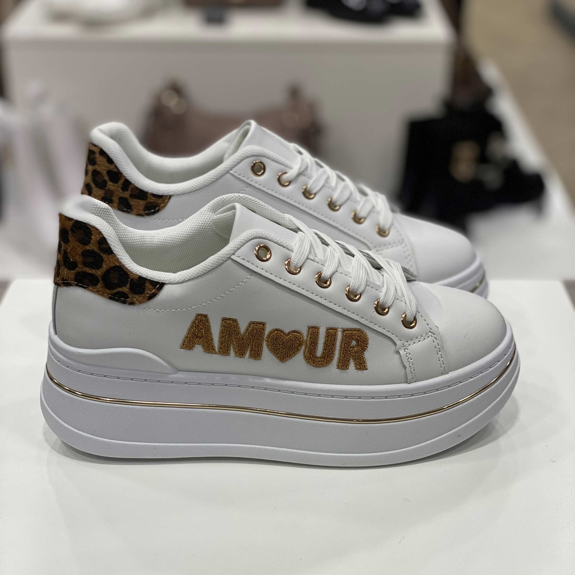 Sneakers bianche con scritta 'AMOUR', cuore glitterato e dettagli leopardati, vista laterale per evidenziare il design romantico e moderno
