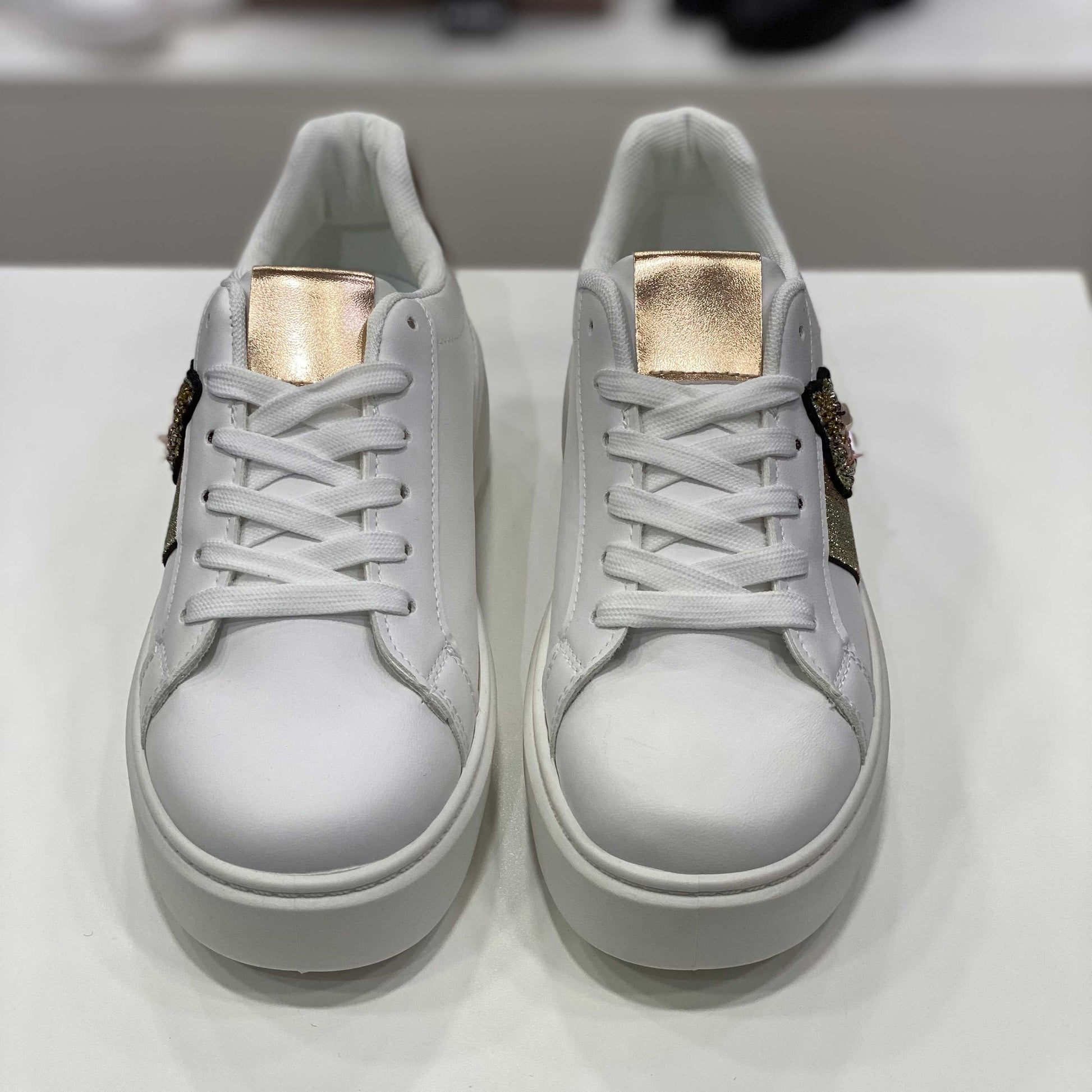 Sneakers bianche con applicazione gioiello e dettagli dorati, vista frontale per evidenziare il design raffinato
