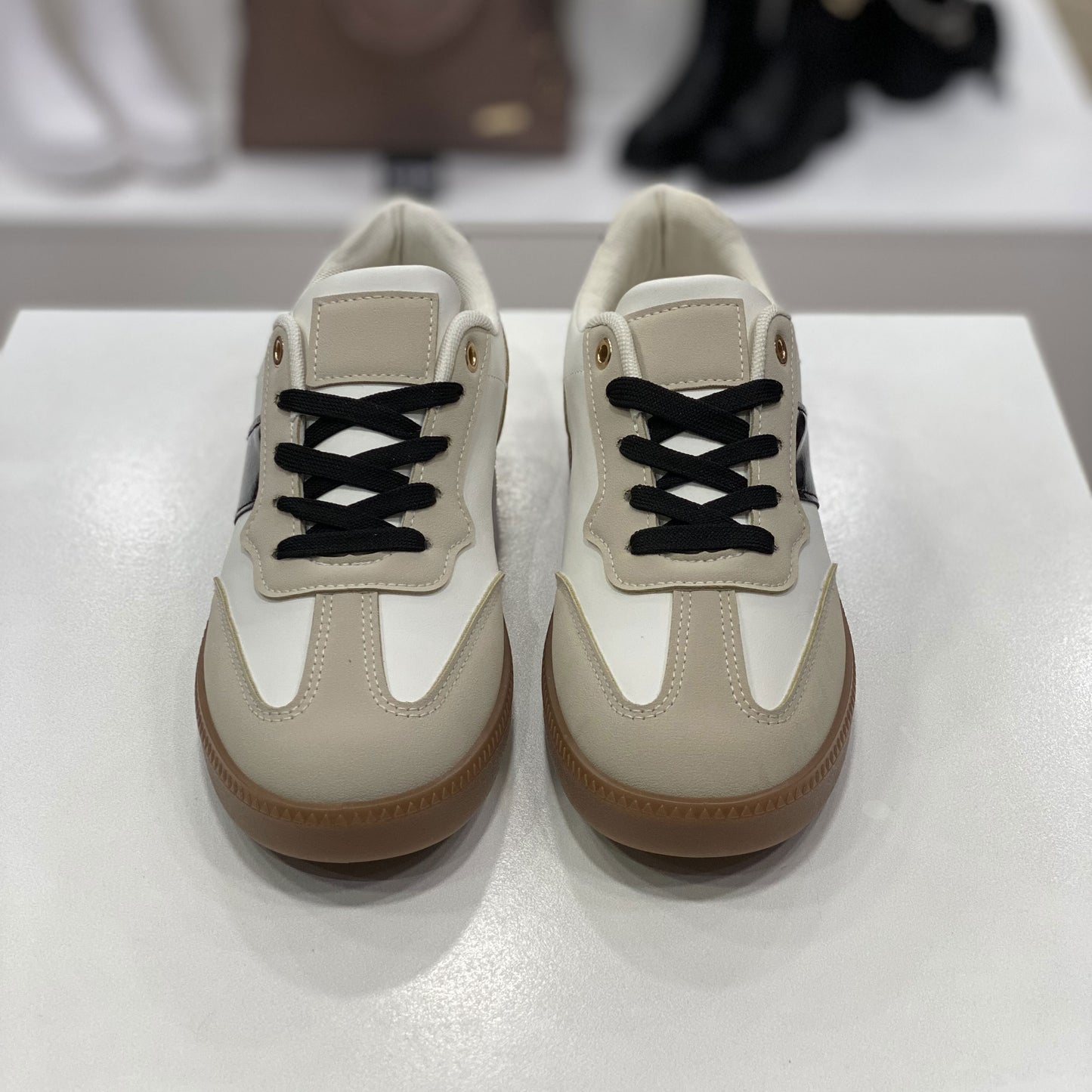 Sneakers beige e bianche con suola in gomma, vista frontale su sfondo neutro