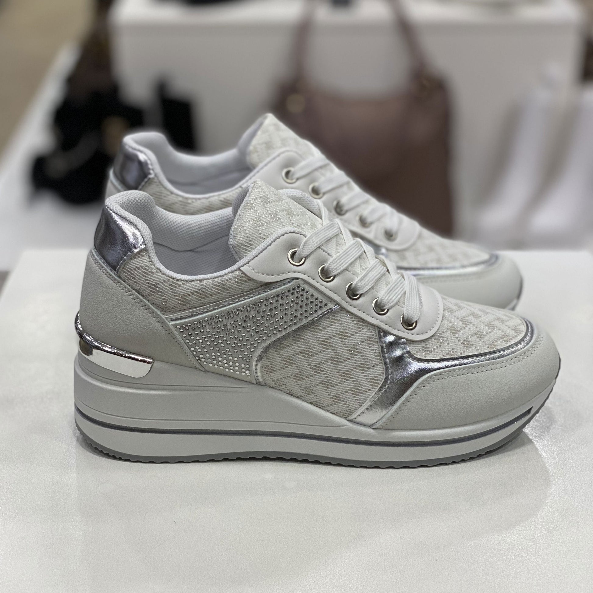 Sneakers bianche con dettagli metallici argentati, vista laterale per mostrare il design e i dettagli della scarpa