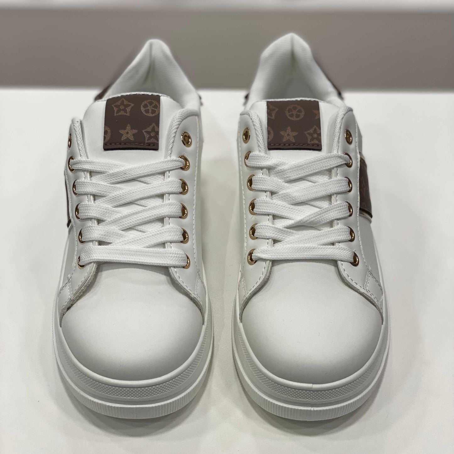 Sneakers bianche con dettagli monogram marroni, vista frontale per evidenziare il design moderno