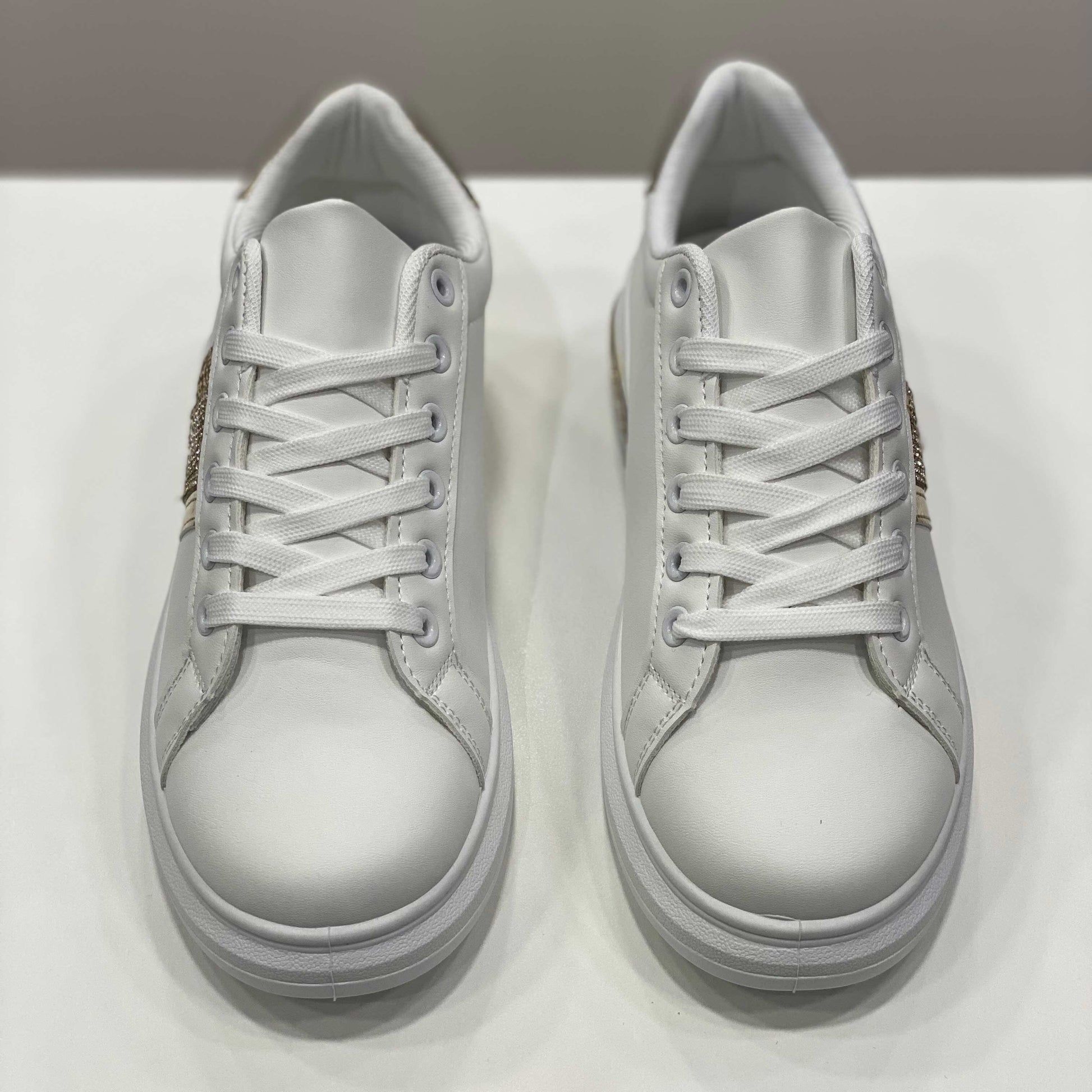 Sneakers bianche con fascia glitterata dorata e dettagli eleganti, vista frontale su sfondo neutro