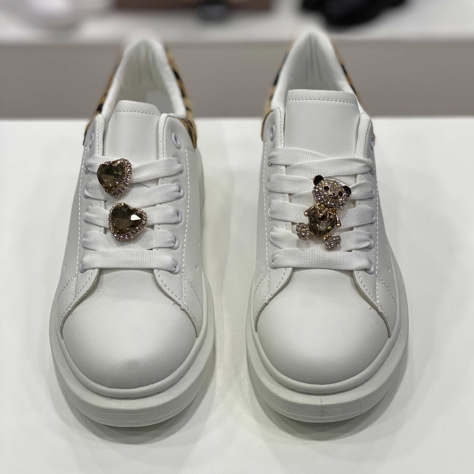 Sneakers bianche con gioielli decorativi e tallone leopardato, vista frontale per evidenziare i dettagli eleganti