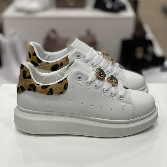 Sneakers bianche con decorazioni gioiello sui lacci e tallone leopardato, vista laterale su sfondo neutro