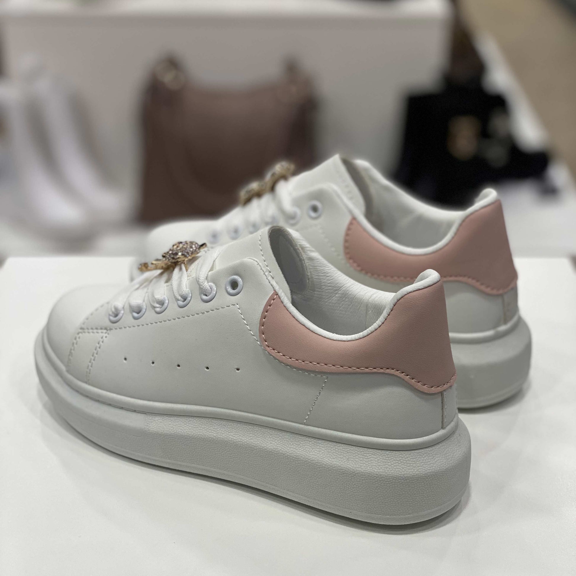 Parte posteriore di sneakers bianche con tallone rosa pastello e suola alta, vista del tallone su sfondo neutro