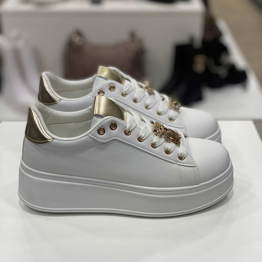 Sneakers bianche con gioiello a forma di gatto e cuore, dettagli dorati sulla linguetta e tallone, vista laterale per evidenziare il design elegante