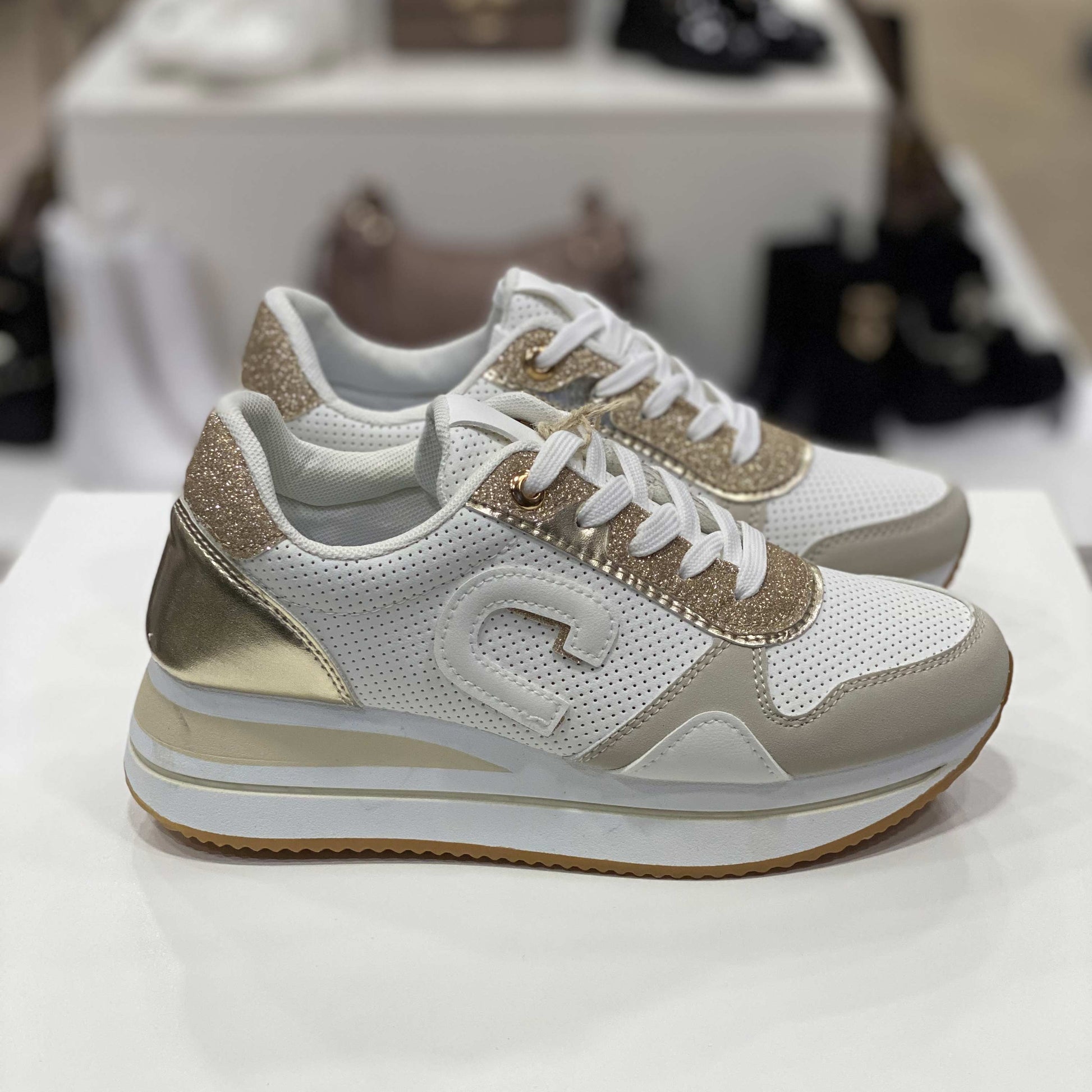 Sneakers bianche con glitter dorati e dettagli metallici, vista laterale per mostrare il design e gli elementi decorativi