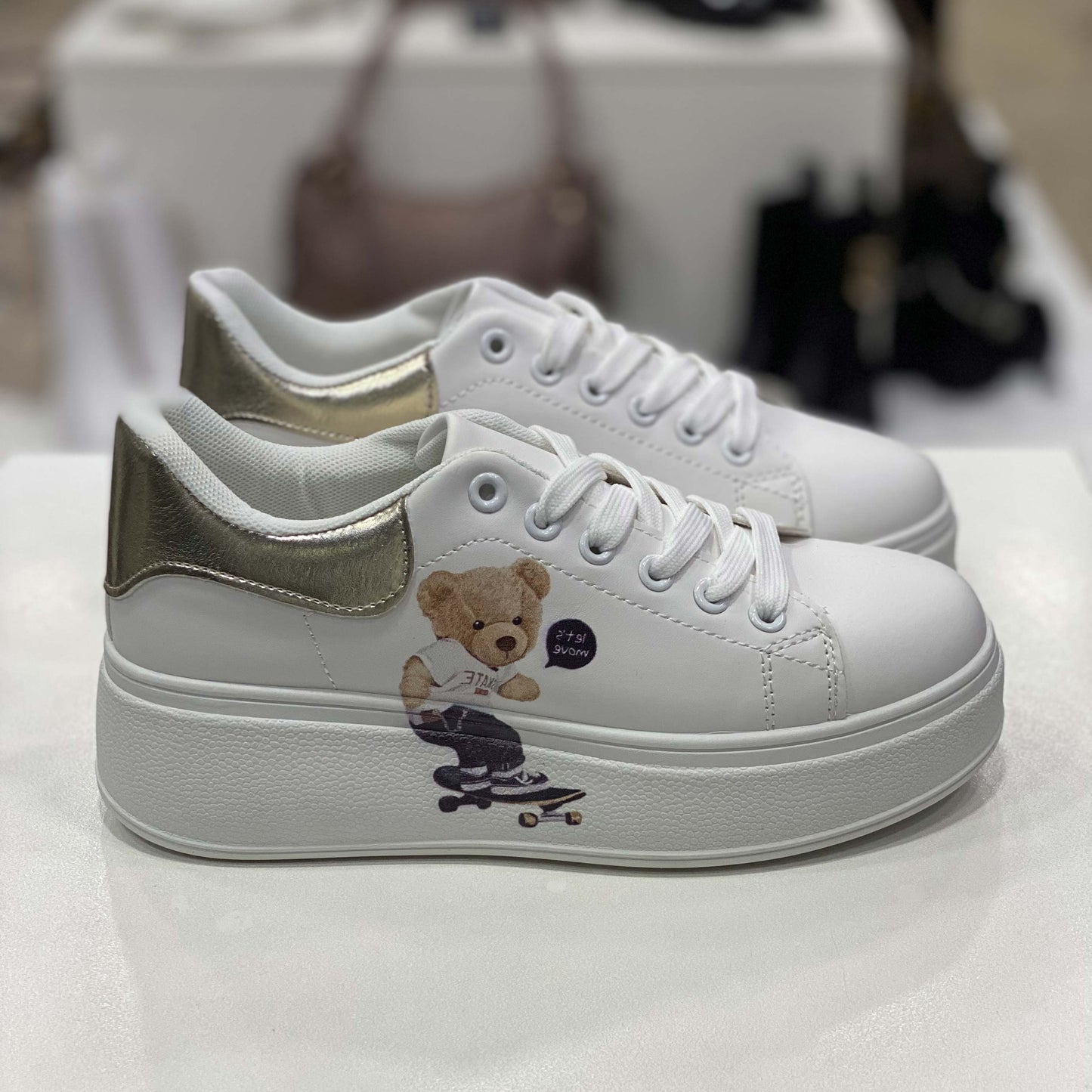 Sneakers bianche con stampa di orsetto e dettaglio oro sul tallone, vista laterale per mostrare il design e la stampa decorativa