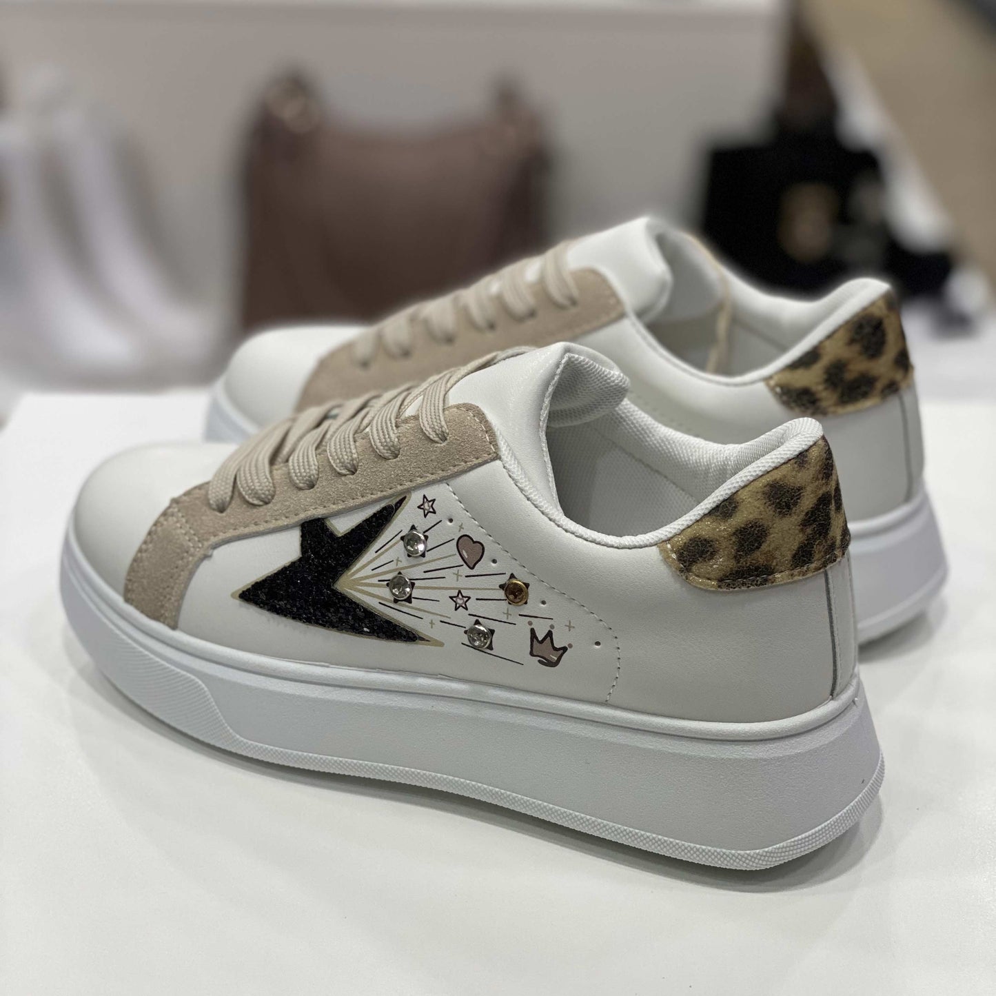 Parte posteriore di sneakers bianche con tallone decorato leopardato e dettagli eleganti, vista del tallone su sfondo neutro