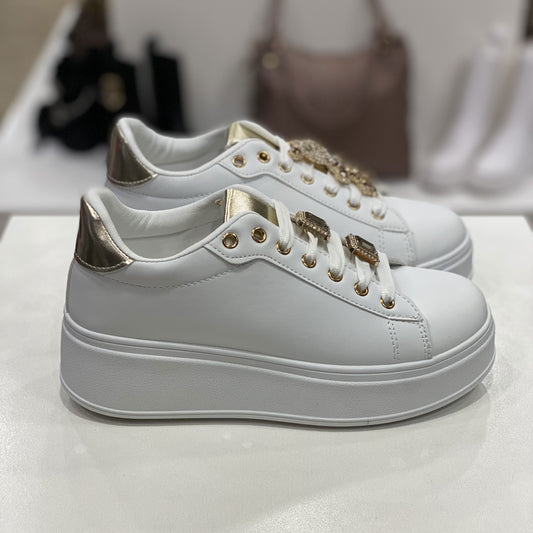 Laterale di sneakers bianche con un tocco dorato sia sulla linguetta che sul tallone. La suola rialzata e i dettagli in oro sulle decorazioni le rendono una scelta audace e contemporanea per chi vuole distinguersi.