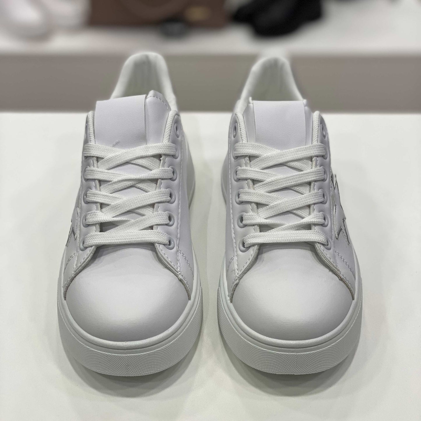 Sneakers bianche con decorazioni cuori e tallone argento, stella nera e scritta 'Super Girl', vista frontale su sfondo neutro