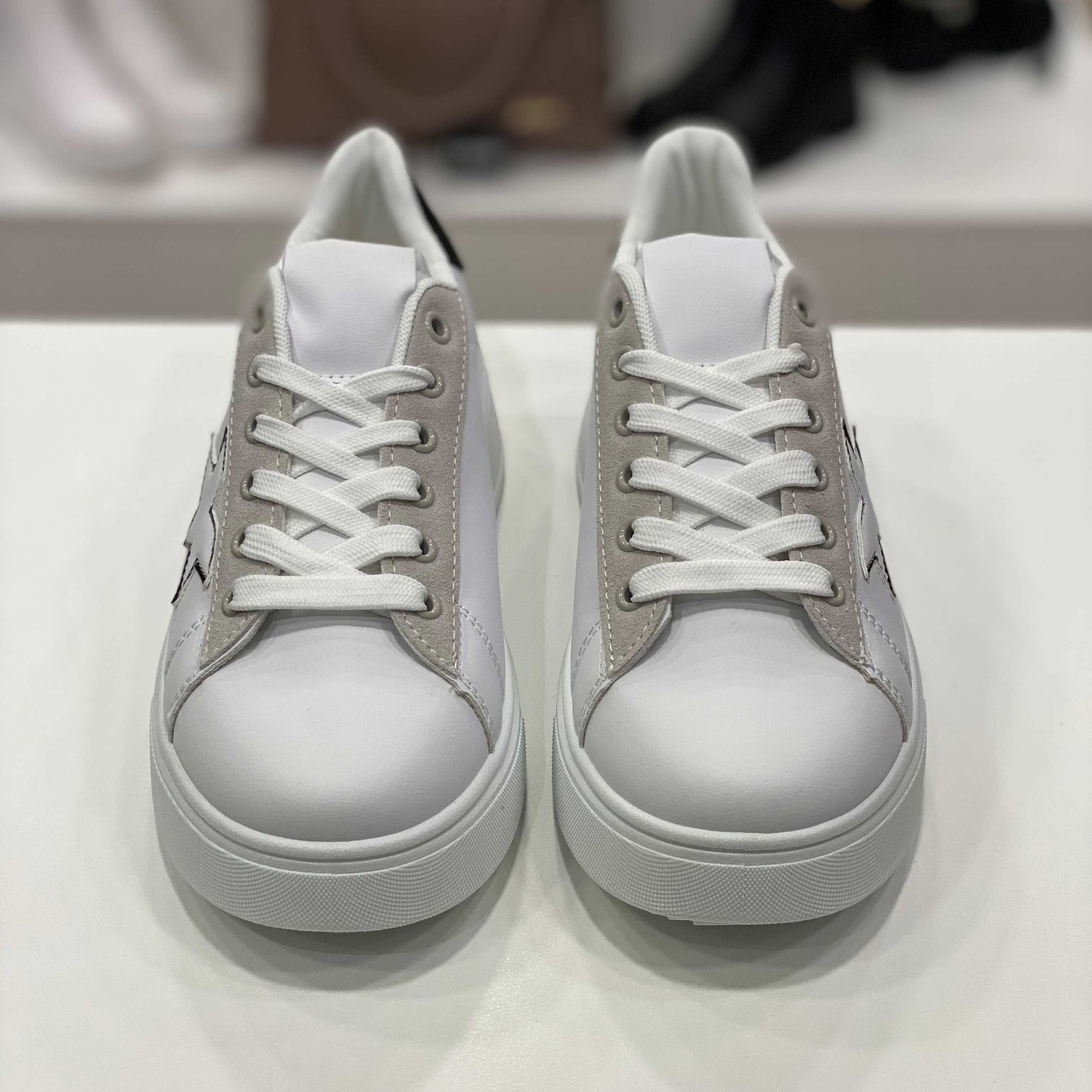 Sneakers bianche con decorazioni cuori e tallone nero, stella nera e scritta 'Super Girl', vista frontale su sfondo neutro