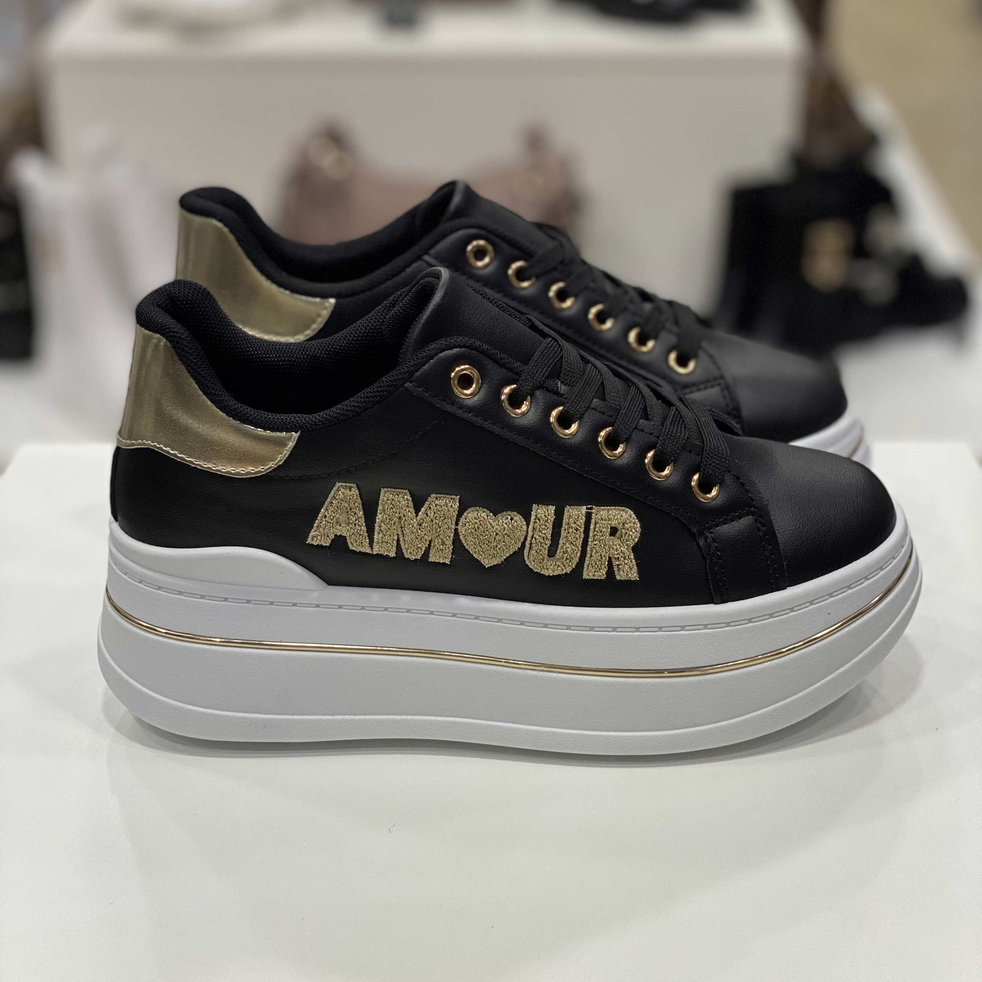 Sneakers nere con scritta 'AMOUR', cuore glitterato e dettagli dorati, vista laterale per evidenziare il design romantico e moderno