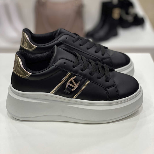 Sneakers nere con dettagli dorati e suola alta bianca, vista laterale per mostrare il design sofisticato