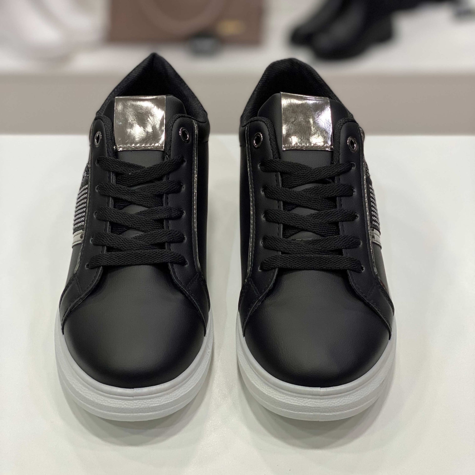 Sneakers nere con fascia glitterata e dettagli eleganti argentati, vista frontale su sfondo neutro