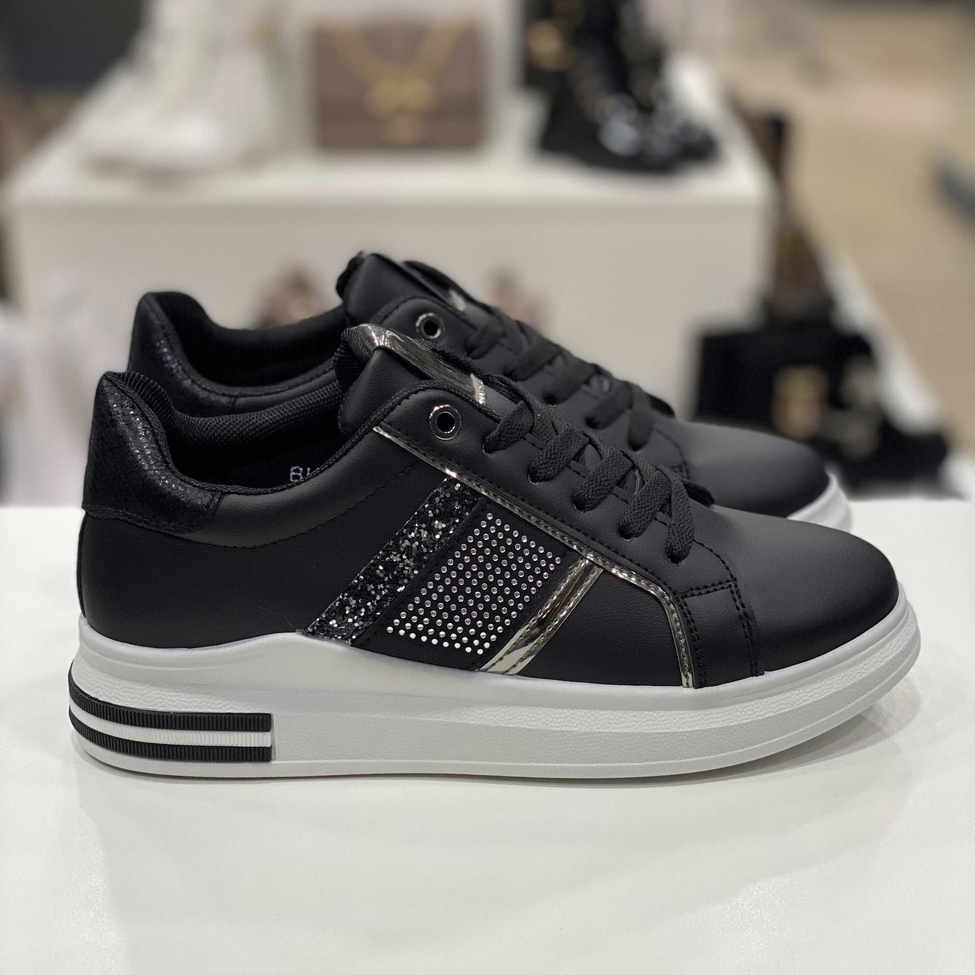 Sneakers nere con fascia glitterata e dettagli argento, vista laterale su sfondo neutro