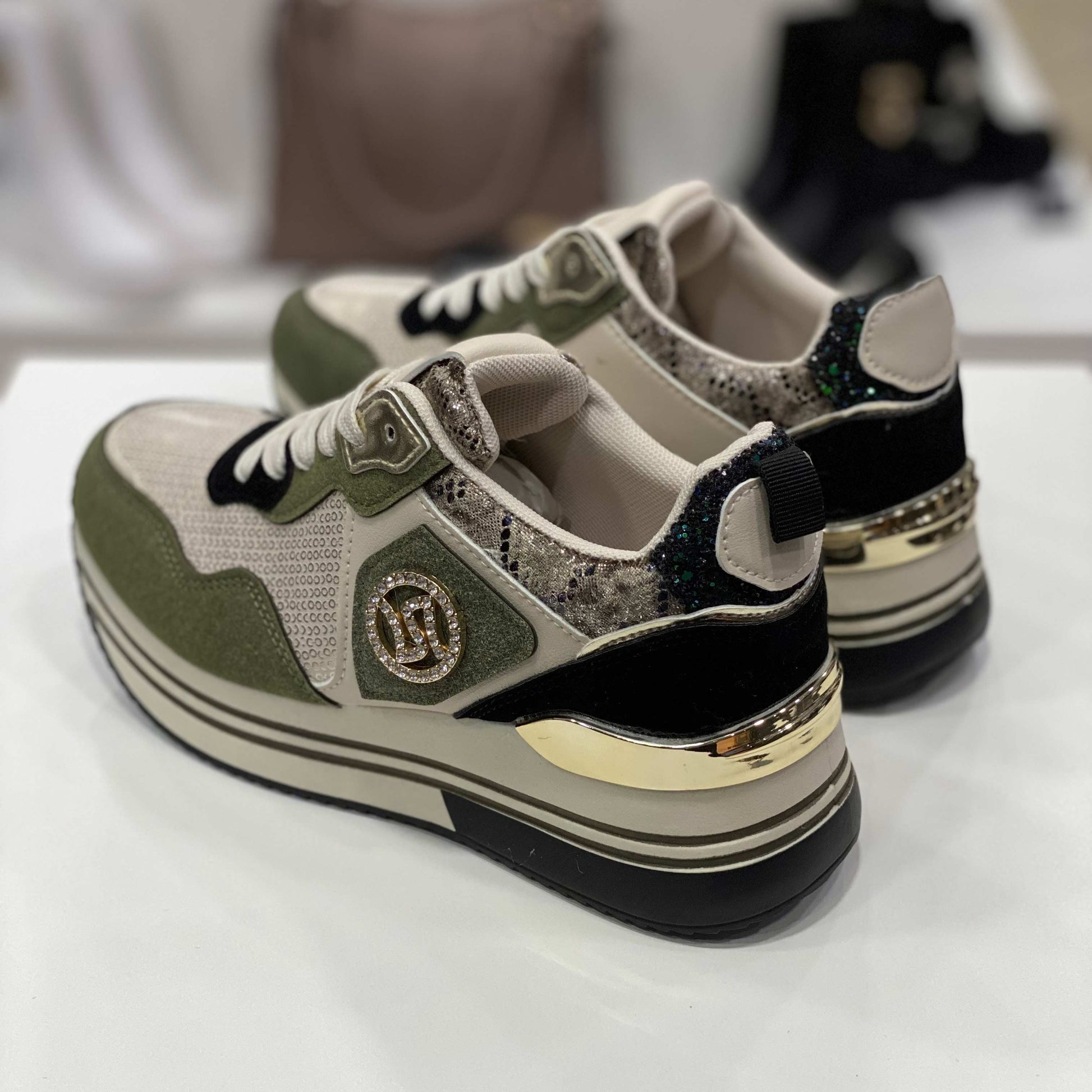 Parte posteriore di sneakers verdi con dettagli glitter e tallone animalier, vista su sfondo neutro